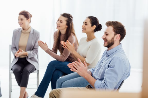 smiling-group-of-people-sitting-and-applauding-dur-XDEQSQZ